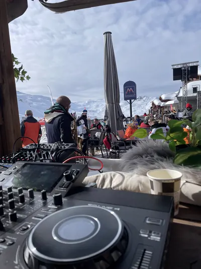Régie sur une terrasse de montagne, saxophoniste de dos, pistes enneigées