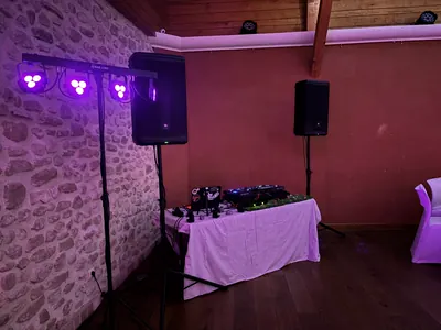 Table DJ, enceintes et barre de lumières dans une salle aux murs de pierre