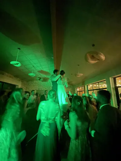 Piste de mariage sous une lumière verte, les mariés portés par les invités