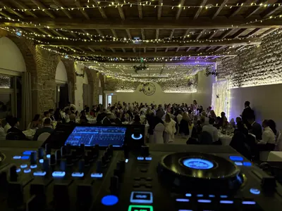 Salle de réception pleine sous les guirlandes, vue depuis la régie du DJ