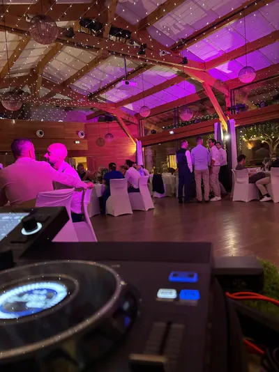 Salle de réception en bois éclairée en rose, invités entre les tables