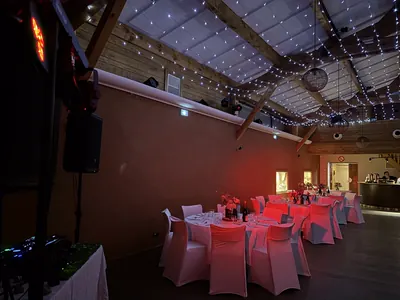 Salle de réception dressée, tables rondes et guirlandes lumineuses