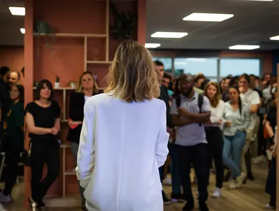 Intervenante de dos devant une équipe réunie dans des bureaux