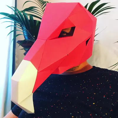 Performer masqué, tête d'oiseau en papier, sous les palmiers
