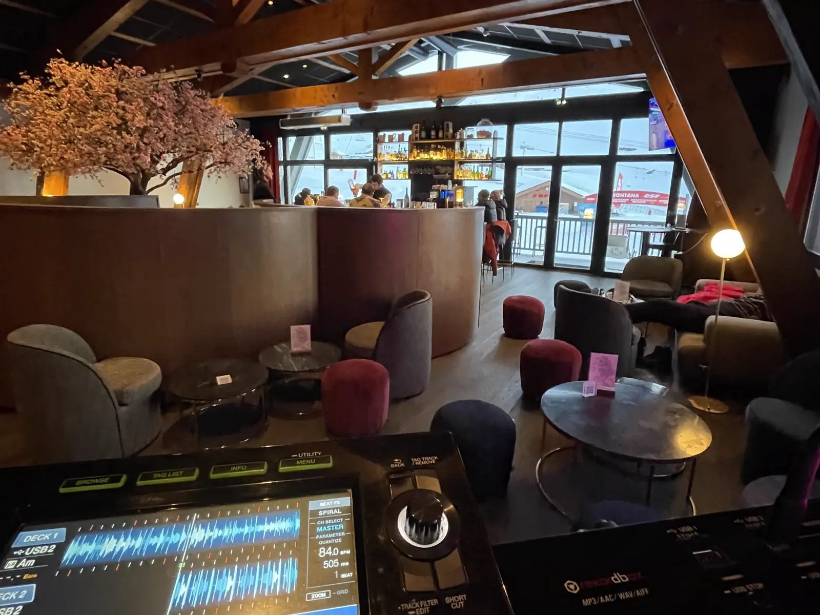 Régie DJ installée dans un lieu de réception lumineux, salon et bar en arrière-plan, avant l'arrivée des invités